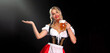 Young sexy Oktoberfest girl waitress, wearing a traditional Bavarian or german dirndl, serving big beer mugs with drink isolated on black background. Woman pointing to looking left.