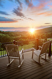 Fototapeta Miasta - Two rocking chairs on a balcony overlooking a beautiful sunrise