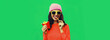 Portrait of stylish happy smiling young woman eating french fries fast food wearing pink hat on green colorful background