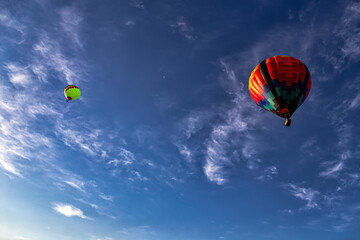 two lonely balloons fly high across the vast expanses of the sky among the clouds, touching the tops