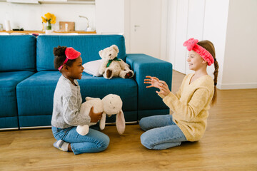 Wall Mural - Little interracial sisters playing with stuffed toys together