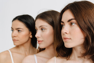 Three beautiful brunette women posing at camera in profile