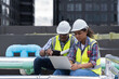 © amorn - Group of African American engineer worker working in sewer pipes area at construction site. Male engineer and woman engineer work with laptop computer for maintenance sewer pipes