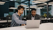 © Yuliia - Two multicultural professional male co-workers men colleagues sit at office use laptop discuss internet project hold negotiation choosing business profitable contract cooperation teamwork partnership