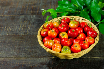 Acerola Cherry or Barbados Cherry on basket with green leaf on rustic wooden background.