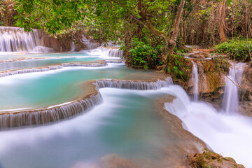 Magical turquoise blue colours of Kuang Si waterfalls Luang Prabang Laos. these waterfalls in the Mountains of Luang Prabang Laos flow all year round in the natural national park rainforest 