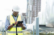 © amorn - Male engineer or male technician work with digital tablet at construction site area. African American male engineer worker check or maintenance pipe system for ventilation and air conditioning