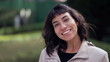 © Marco - Happy South American young woman portrait face smiling at camera standing outside. Young latin person in 20s. Tracking shot in motion