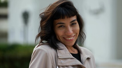 Wall Mural - Young woman wearing jacket smiling at camera. A South American latin girl portrait face closeup