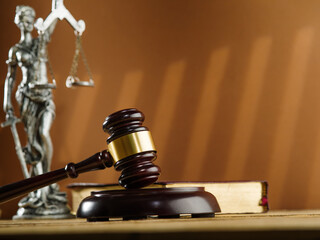 Wall Mural - Judgment and Justice. A wooden gavel of a judge, an open book - the Constitution and a bronze figurine of the goddess of justice - Themis on a beige background.