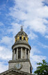 London, Great Britain - July 3, 2022: Closeup of clock tower with golden caryatid statues of St. Marylebone Parish Church under blue cloudscape. Green foliage 