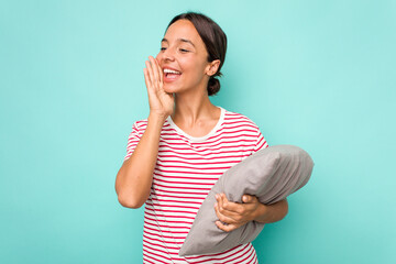 Wall Mural - Young hispanic woman holding a cushion isolated on white background shouting and holding palm near opened mouth.