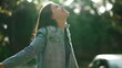 Carefree happy woman arms raised outside looking at sky feeling grateful. Person celebrating life standing in nature sunlight