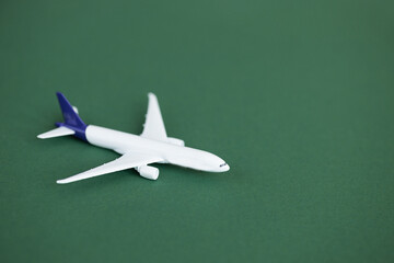 Wall Mural - Miniature toy airplane on green background. Summer holiday air travel by plane concept.