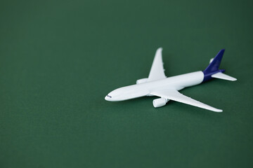 Wall Mural - Miniature toy airplane on green background. Summer holiday air travel by plane concept.