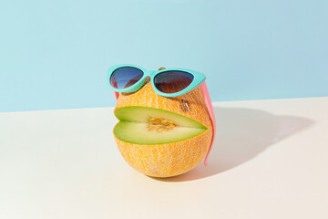 Abstract creative summer fruit scene made of cut melon with sunglasses on isolated pastel blue and beige background. Sun and shadow. The idea of happy emoticon. Ocean beach party or vacation concept.