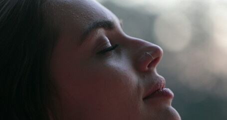 Young woman face opening and closing eyes. Girl meditating and in contemplation looking up to the sky with hope and faith