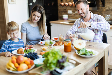 Wall Mural - Young happy family enjoying in their breakfast time in dining room