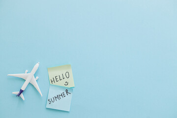 Wall Mural - Miniature toy airplane on color background and word hello summer. Trip by airplane.