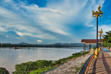 Boulevard With Ornate Lamp Posts And The Mekong River At Chiang Khan, Province Of Loei, Thailand. The Other Bank Of The River Is In Laos.
