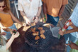 © Seventyfour - High angle at group of young people grilling chicken meat during barbeque party outdoors in Summer and drinking beer