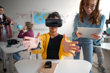 Teenage students wearing virtual reality goggles at school in computer science class