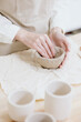 © MyJuly - woman ceramist in the workshop makes mugs out of clay. a small business or hobby is the creation of ceramic products. an oriental young woman ceramist makes dishes and vases out of clay. handmade