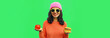 Leinwandbild Motiv Portrait of stylish happy smiling young woman making choice showing burger fast food and apple on green colorful background