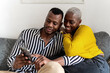 © Ezequiel Giménez/Stocksy - Black couple using smartphone on sofa