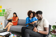 © Valentina Barreto/Stocksy - Mixed coworkers on sofa in cowork rest area