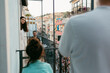 © Jimena Roquero/Stocksy - Neighbors talking through the balconies over city street