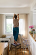 © STUDIO TAURUS/Stocksy - Woman Hanging Curtains At Home