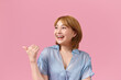 © Marc Tran/Stocksy - Smiling young woman isolated on pink background point with finger