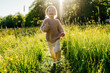 © Sergey Narevskih/Stocksy - Child laughing and running in grassy field