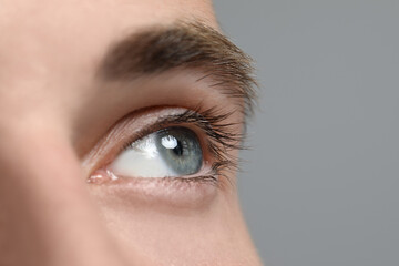 Wall Mural - Closeup view of young man with beautiful eyes on grey background