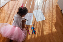 Little Girl Dressed As A Ballerina Coloring A Drawing At Home