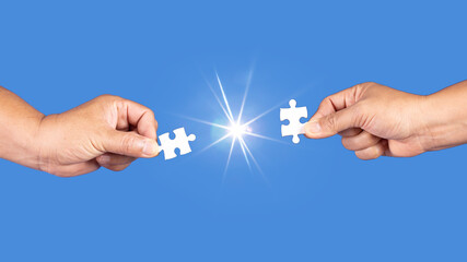 Hands holding jigsaw puzzles piece with clear blue background, success business, solution strategy, teamwork partnership concept