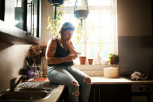 Worried Woman Reading Fake News On Phone, Searching Social Media Or Receiving Bad News On Technology During Lockdown. Browsing Or Texting While Looking Stressed, Concerned And Anxious In Home Kitchen