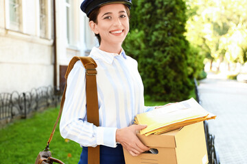 Wall Mural - Young postwoman with box and letters outdoors