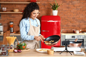 Sticker - Young woman putting pasta onto plate while recording video class in kitchen