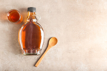 Wall Mural - Bottle and glass of maple syrup on light background