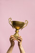 © Pixel Stories/Stocksy - Winner holding golden cup. Success and achievement, victory concept.