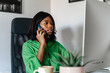 © David Prado/Stocksy - Black woman talking on smartphone while working