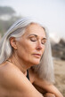 © Alba Vitta/Stocksy - Portrait of relaxed mature woman at the beach