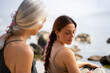 © Alba Vitta/Stocksy - Mother braiding hair to daughter at the beach
