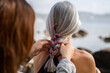 © Alba Vitta/Stocksy - Daughter braiding mother's hair in the beach