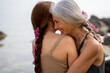 © Alba Vitta/Stocksy - Portrait of hugging mature  mother and adult daughter at the beach