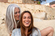 © Alba Vitta/Stocksy - Portrait of mature  mother and adult daughter at the beach