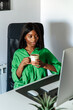 © David Prado/Stocksy - black woman drinking coffee while working on computer