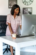 © David Prado/Stocksy - Smiling black woman working on computer at home